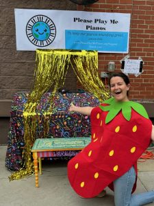 Woman dressed as a strawberry in front of draped piano