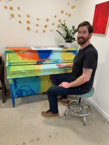 Man at colorfully painted piano