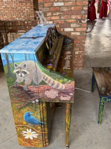 Painted raccoon and bluebird on a piano