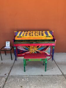 Piano painted in a bright, sunny theme in front of an orange wall