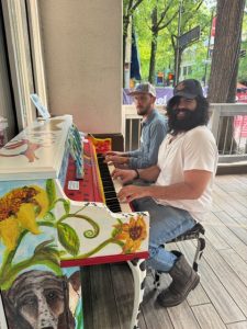 Two men playing painted piano