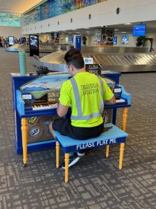 Man plays painted airport piano