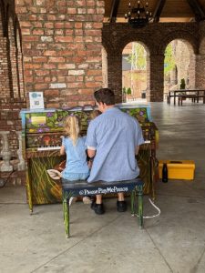 Father and daughter sitting at a painted piano