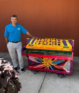 Man standing next to painted piano outdoors