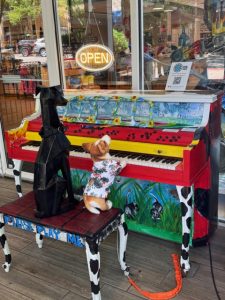 Dog statue and stuffed dog pretend to play a piano painted in a dog theme