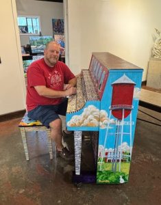 man sitting at painted piano