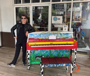 Man dressed as Elvis next to a painted piano