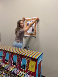 Girl hanging poster behind painted piano