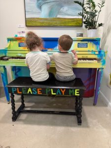 two children play a painted piano