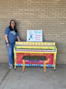 Woman posing next to painted piano