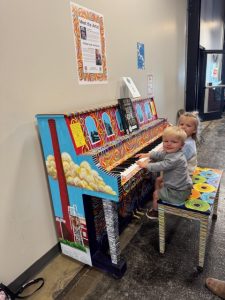 Two children play a painted piano