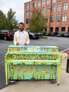 Man standing behind painted piano