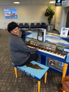 Woman seated at painted piano inside airport