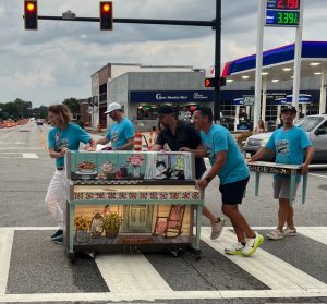 Four people pushing piano across the street