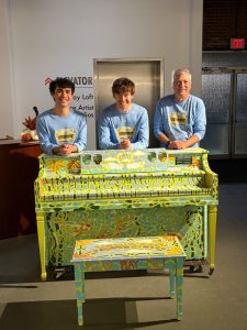 Pianists stand behind painted piano